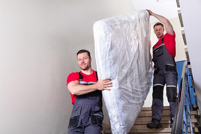 two workers lifting a box spring onto a truck in Albany